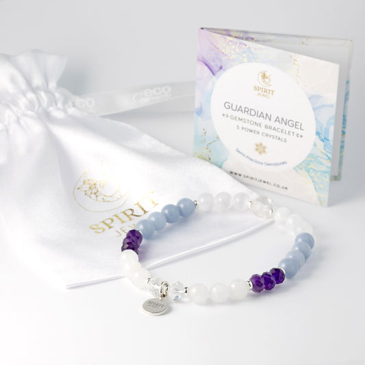 A beaded bracelet with purple and white beads, a white bag with a gold logo, and a package labeled "GUARDIAN ANGEL" and "GEMINIAN BRACELETS + 5 POWER CRYSTALS" on a white background.