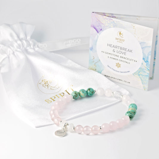 a bracelet with pink and green gemstones, a white satin pouch, and a box of Spirit jewelry.