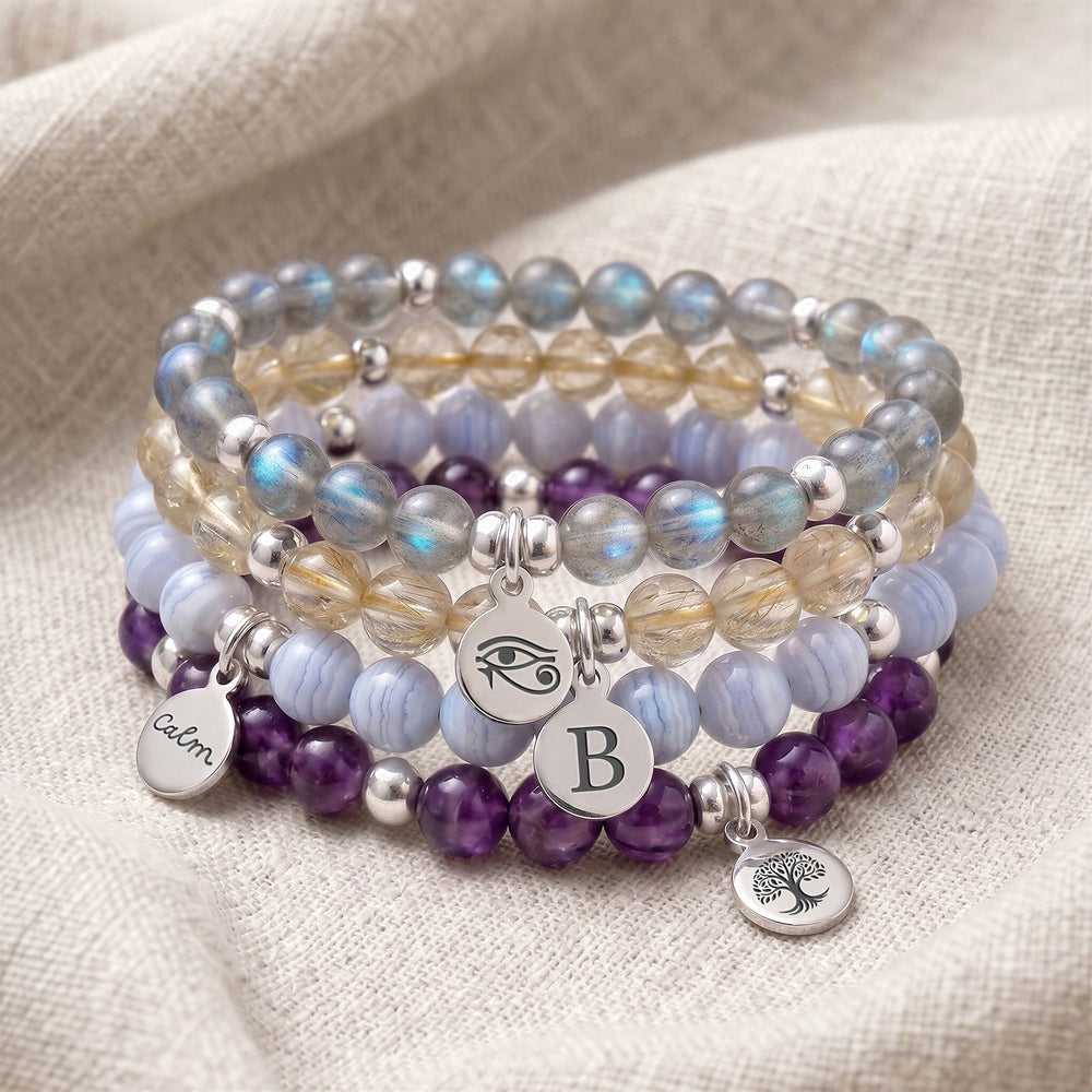 A stack of four personalised crystal gemstone bracelets — Rutilated Quartz, Moonstone, Sunstone, and Strawberry Quartz