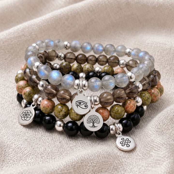 A stack of four personalised crystal gemstone bracelets — Smoky Quartz, Labradorite, Unakite, and Black Tourmaline