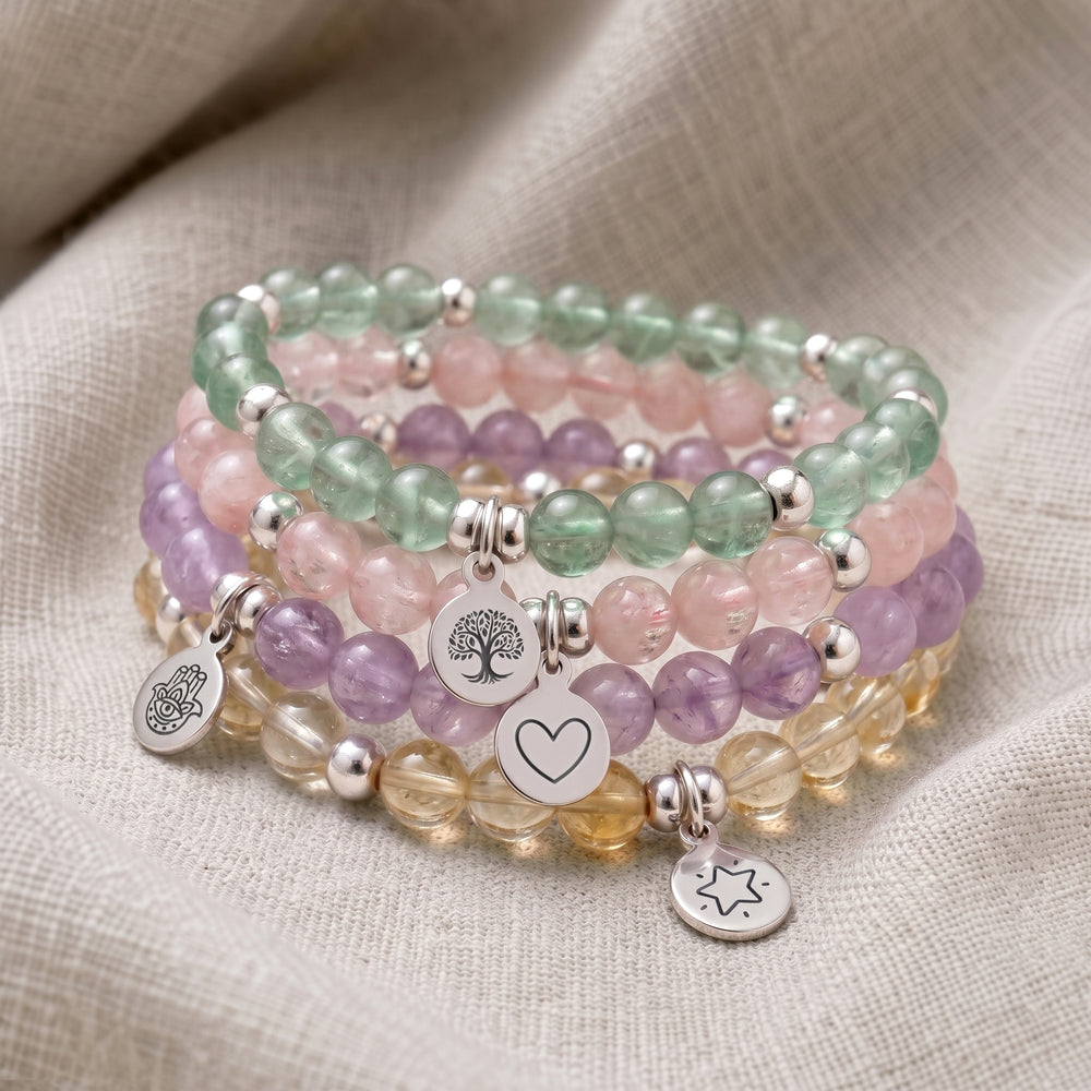 A stack of four personalised crystal gemstone bracelets — Morganite, Green Fluorite, Lavender Amethyst, and Citrine