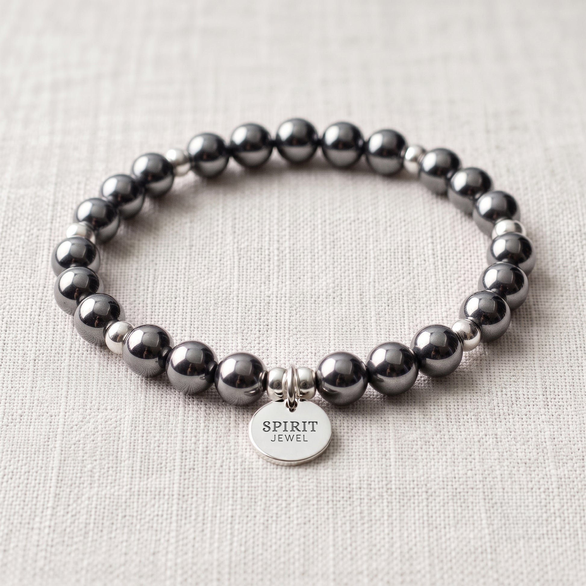 A bracelet made of black beads and silver beads, with a silver charm that says "SPIRIT JEWEL".