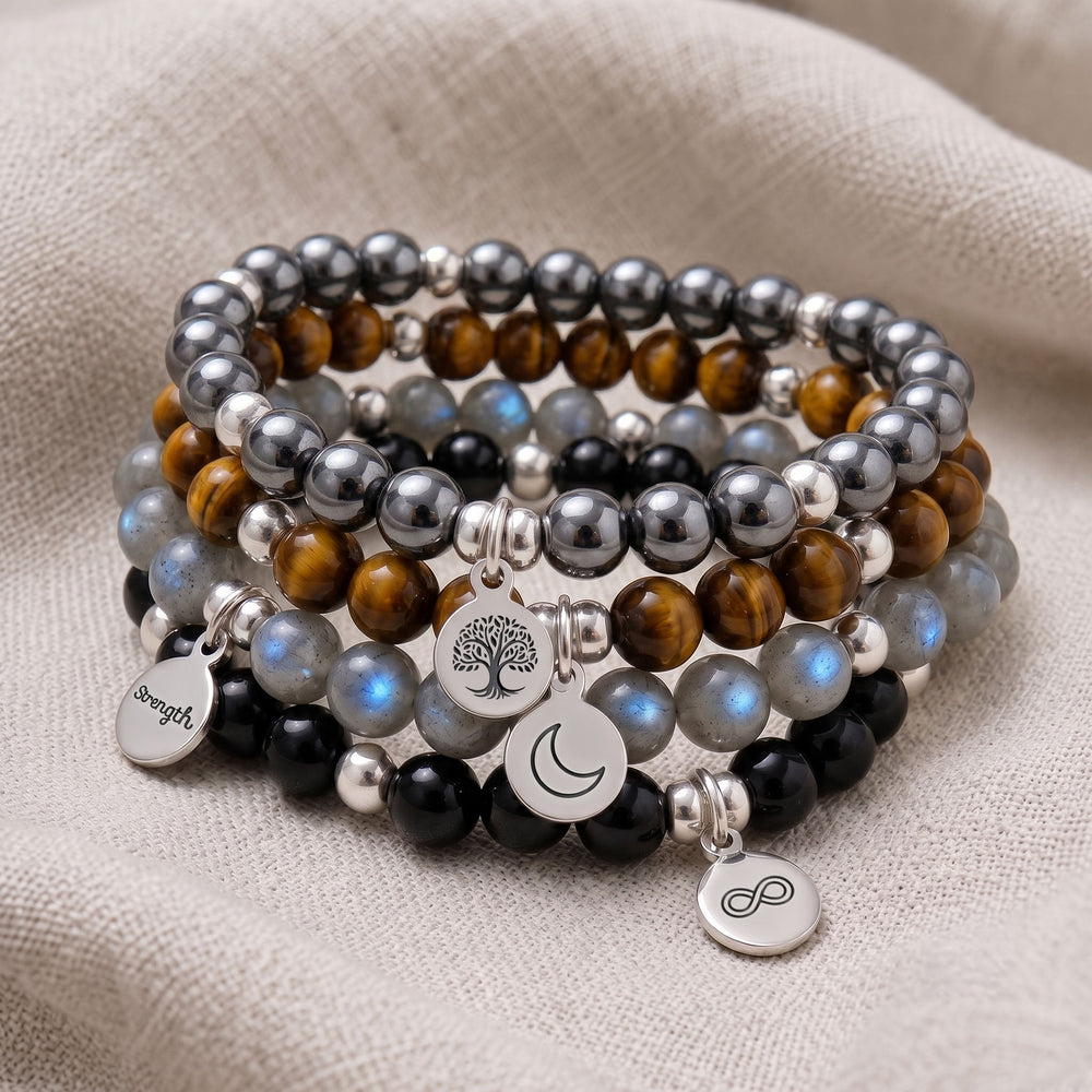 A stack of four personalised crystal gemstone bracelets — Tiger's Eye, Lava Rock, Pyrite, and Shungite
