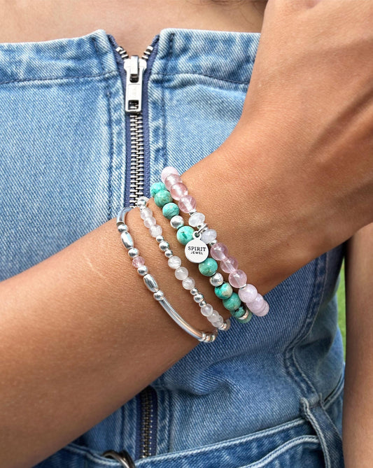 A person wearing a denim outfit and multiple bracelets on their wrist.
