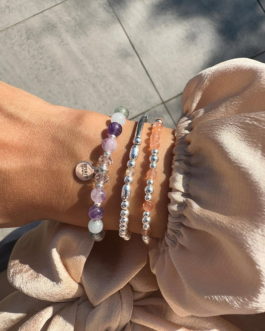 A person's wrist adorned with three bracelets of varying designs and colors.