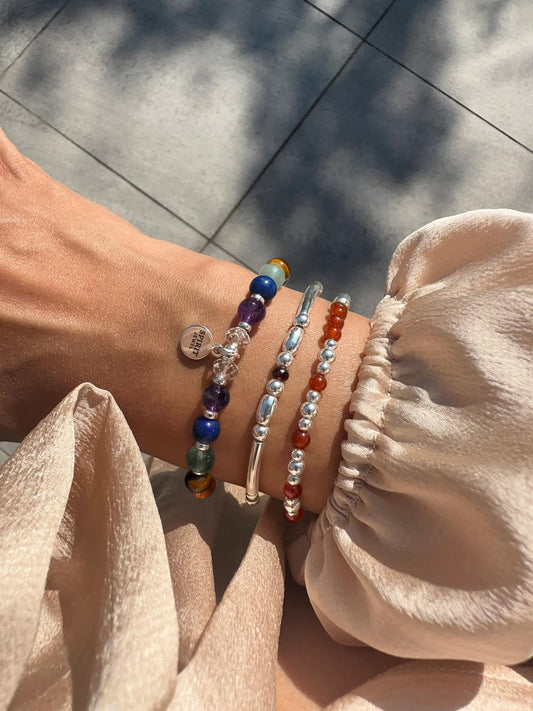 A person's wrist adorned with three bracelets of different colors and designs.