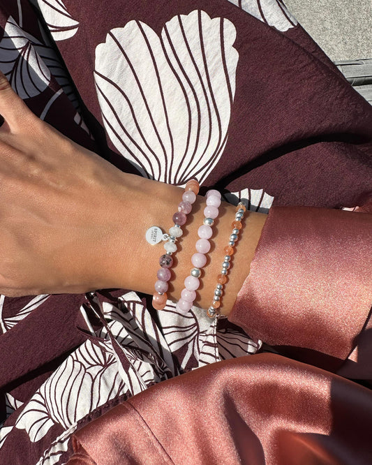 A person's wrist adorned with three bracelets, each with a unique design and color, is visible in the image.