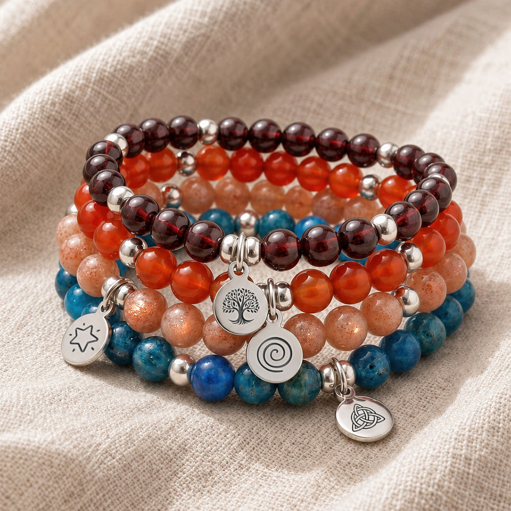 A stack of four personalised crystal gemstone bracelets — Garnet, Carnelian, Sunstone, and Apatite