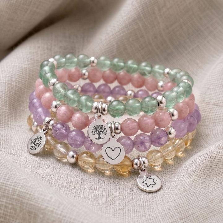 A stack of four personalised crystal gemstone bracelets — Lavender Amethyst, Green Fluorite, Morganite, and Citrine