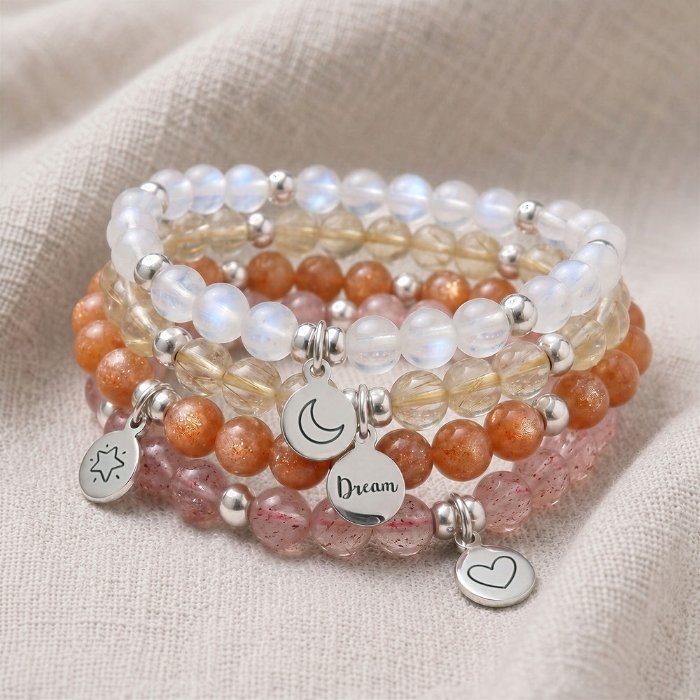A stack of four personalised crystal gemstone bracelets — Strawberry Quartz, Moonstone, Rutilated Quartz, and Sunstone