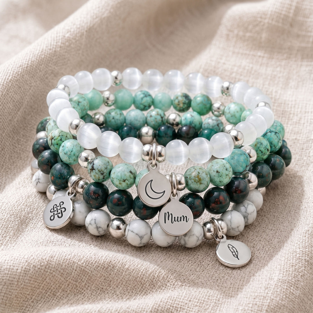 A stack of four personalised crystal gemstone bracelets — Bloodstone, Selenite, Chrysocolla, and Howlite
