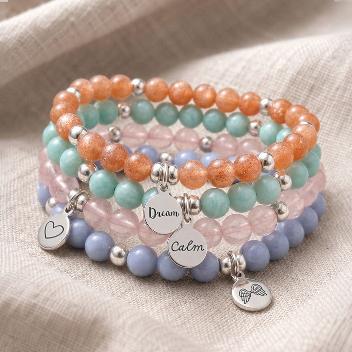A stack of four personalised crystal gemstone bracelets — Angelite, Sunstone, Amazonite, and AAA Rose Quartz