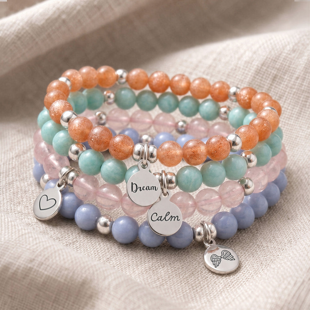 A stack of four personalised crystal gemstone bracelets — Sunstone, Amazonite, AAA Rose Quartz, and Angelite