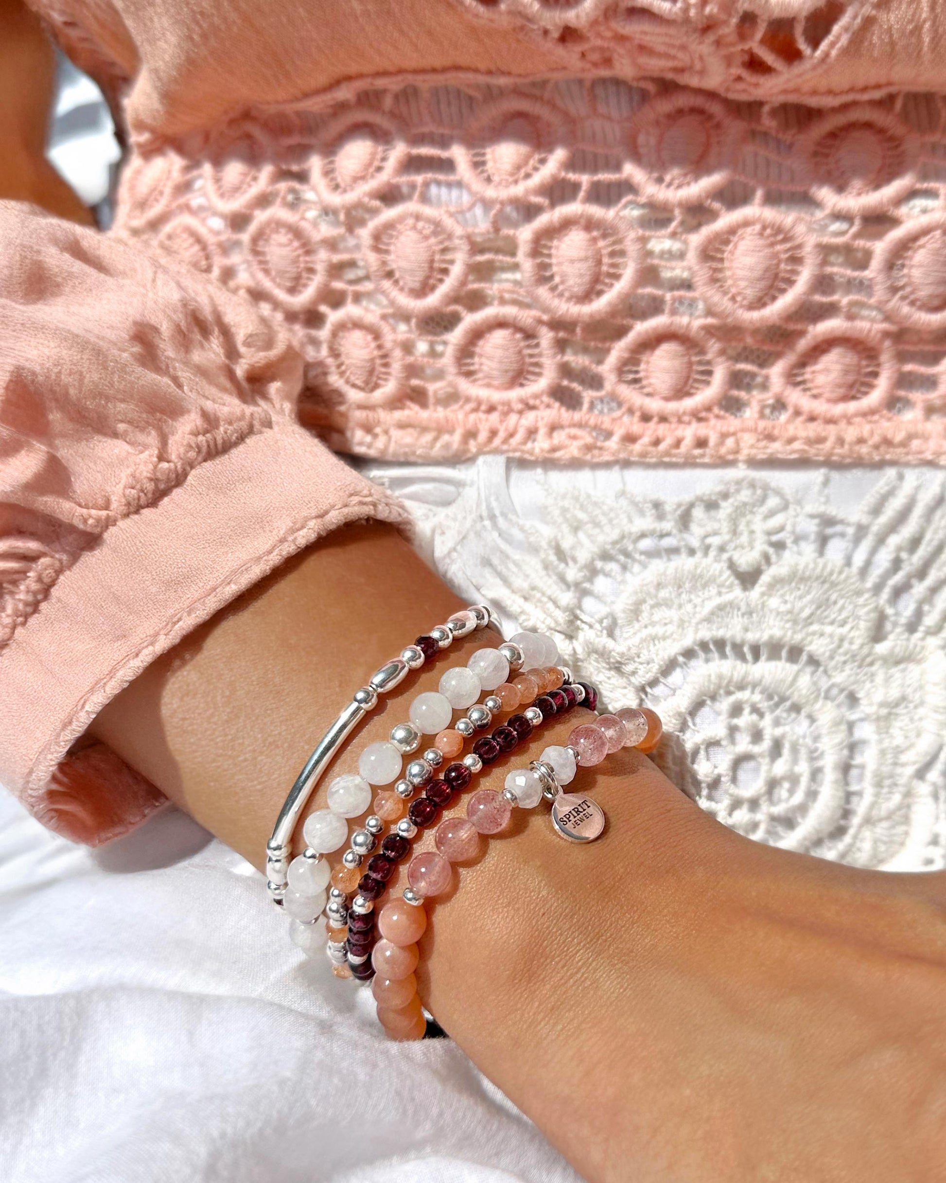 A close-up view of a person's wrist adorned with multiple bracelets, including a beaded bracelet and a charm bracelet.