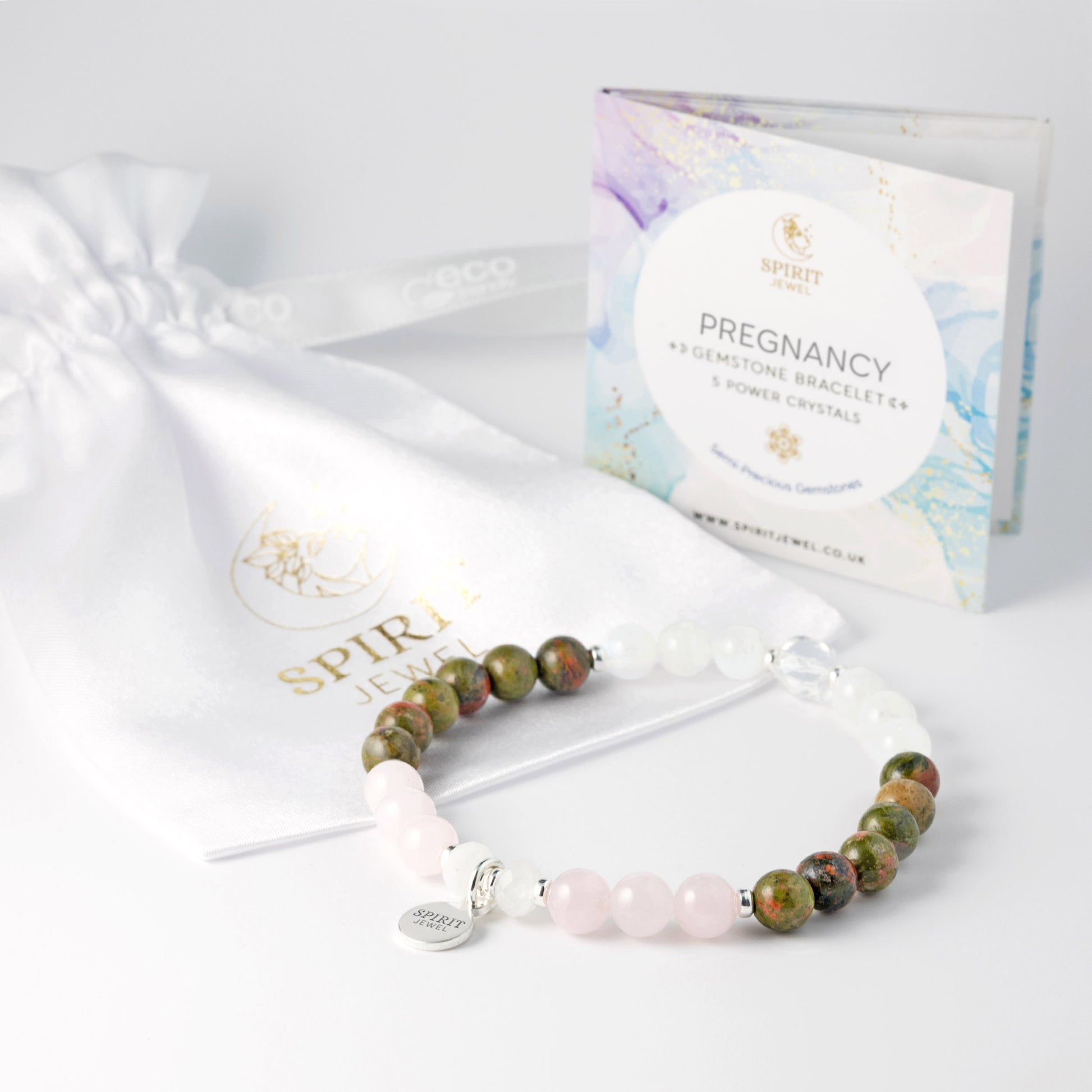 a bracelet with a variety of colored stones, including green, white, and pink beads, and a white drawstring bag with a gold logo and text.
