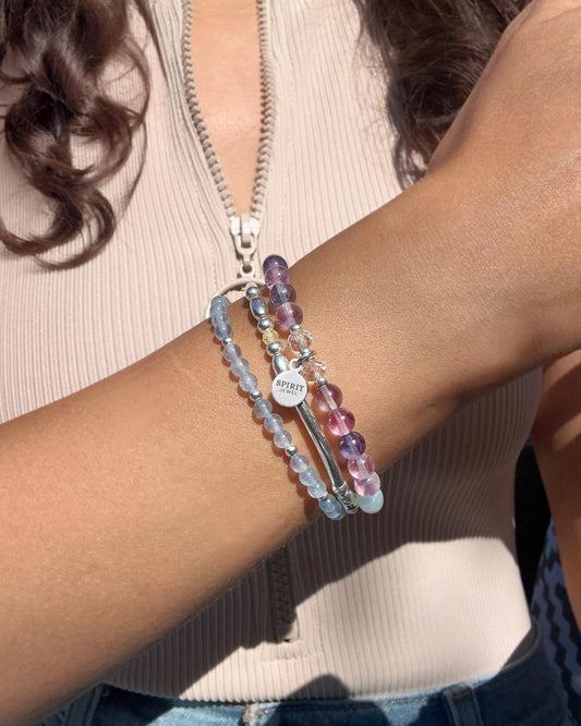 A person wearing a beige top and bracelets on their wrist.